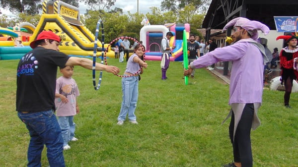 Niños y adultos disfrutando en un parque de diversiones con juegos inflables.