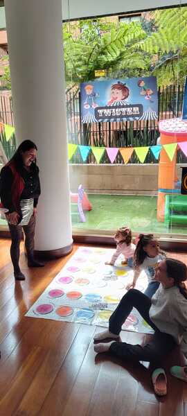 Niños en taller de circo con decoración colorida y área de juegos al aire libre.