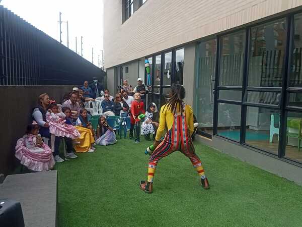 Niña haciendo malabares frente a niños y adultos en un taller de circo.