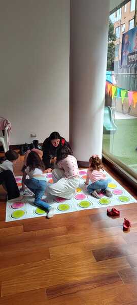 Niños jugando en un taller de teatro en interior con vista a un patio exterior.
