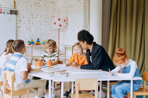 Niños en clase de refuerzo pre-jardín con maestra en aula moderna.