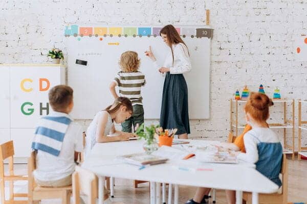 Niños en clase de refuerzo con maestra en aula moderna y colorida.